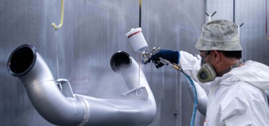 Werker lackiert Werkstücke in Silber