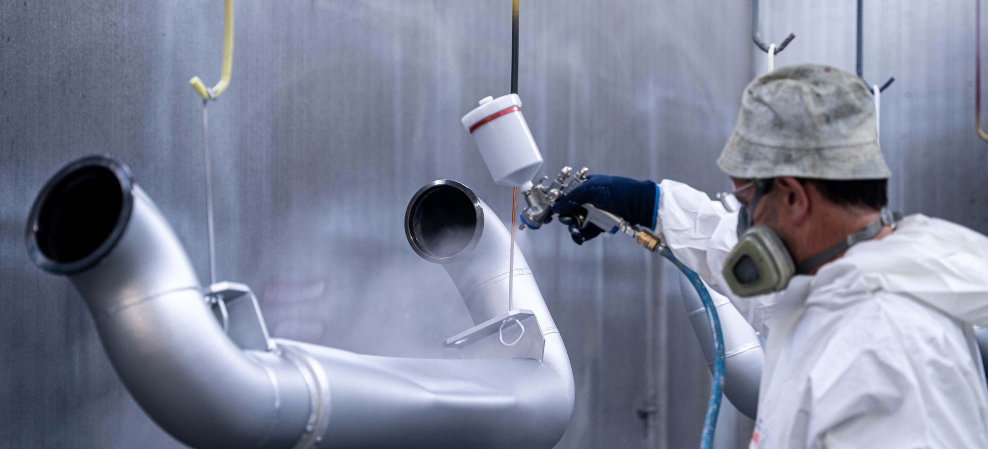 Werker lackiert Werkstücke in Silber