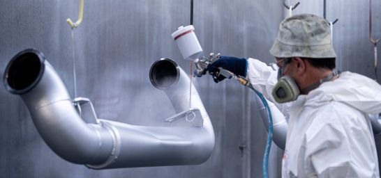 Werker lackiert Werkstücke in Silber