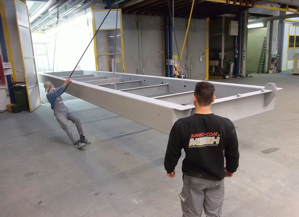 Werker zieht großes Werkstück in die Pulverkabine