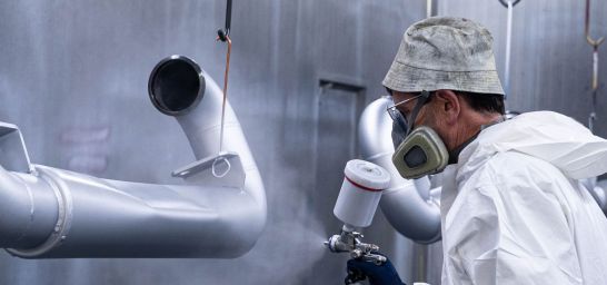 Werker lackiert Werkstücke in Silber