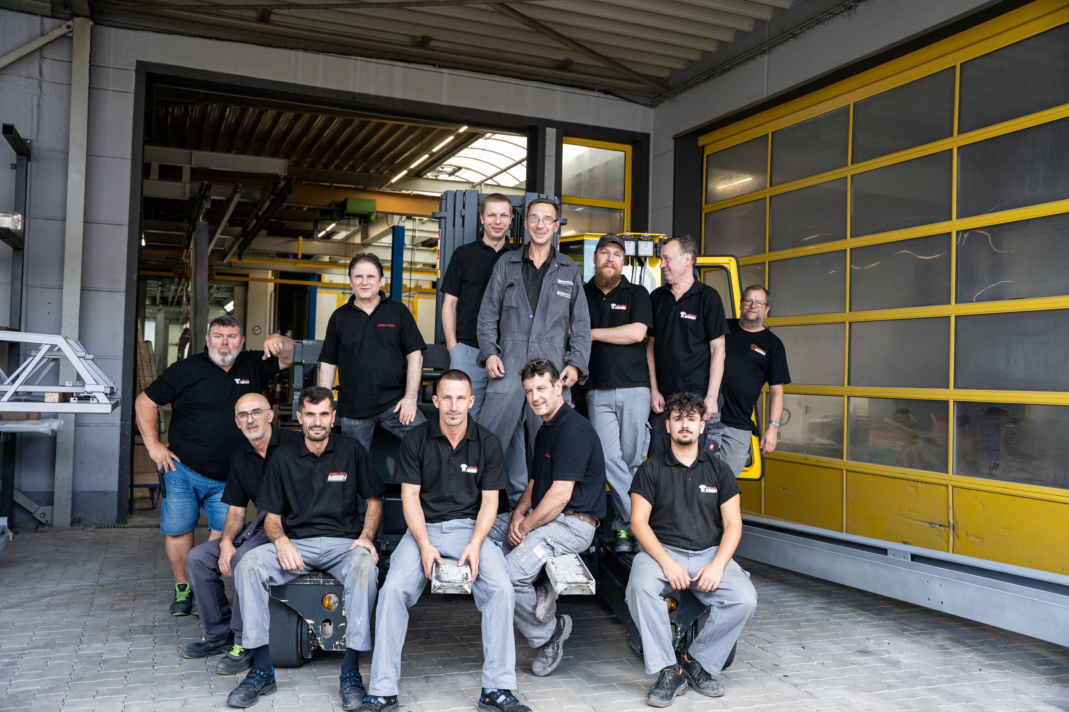 Gruppenbild der Mitarbeiter auf einem 4 Wege-Stapler