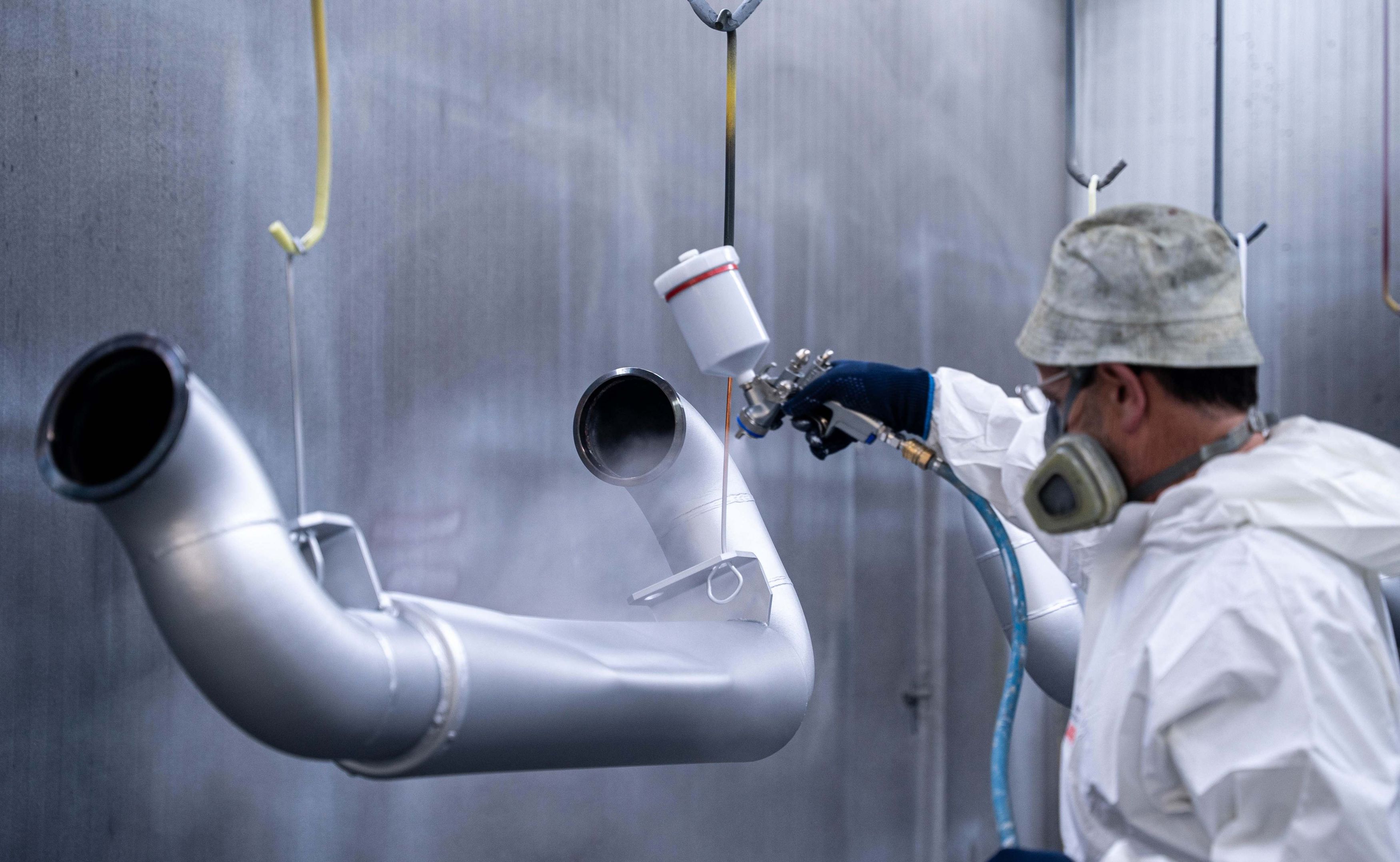 Werker lackiert Werkstücke in Silber