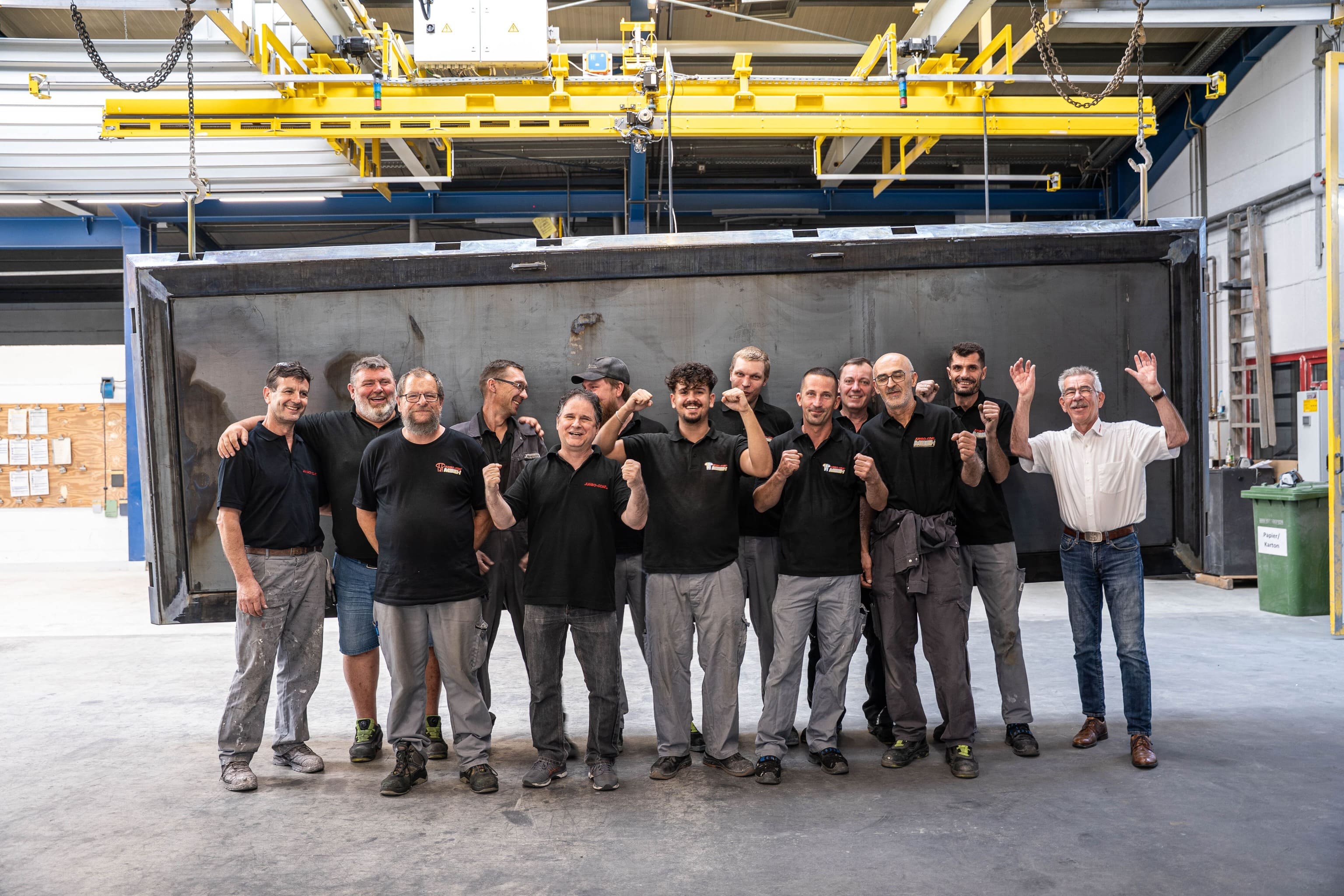 Gruppenbild der Jumbo-Coat Teams vor einem Werkstück